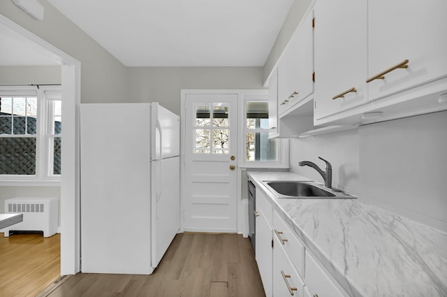 kitchen with radiator heating unit, plenty of natural light, a sink, and freestanding refrigerator