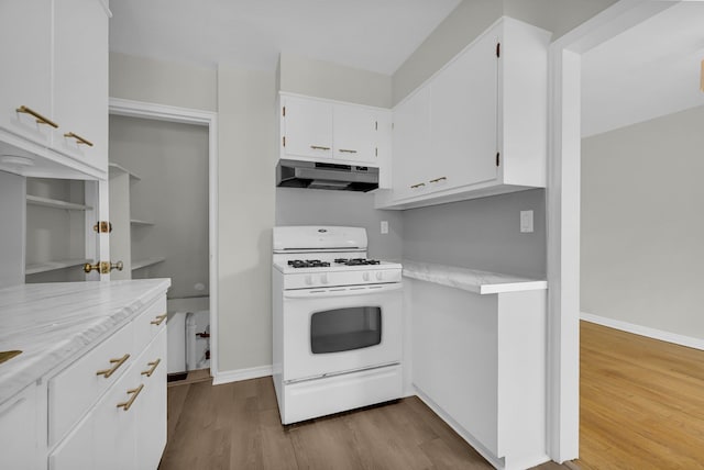 kitchen with gas range gas stove, dark wood-type flooring, white cabinets, under cabinet range hood, and baseboards