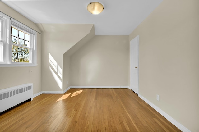 bonus room featuring light wood-type flooring, baseboards, and radiator heating unit