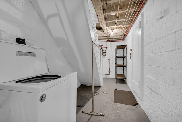 basement featuring concrete block wall and washer / dryer