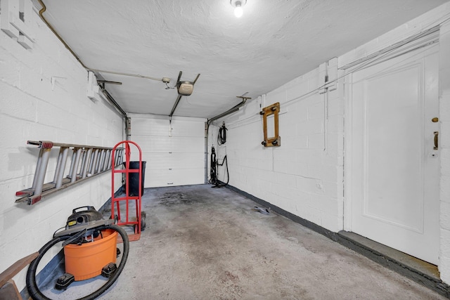 garage featuring concrete block wall and a garage door opener