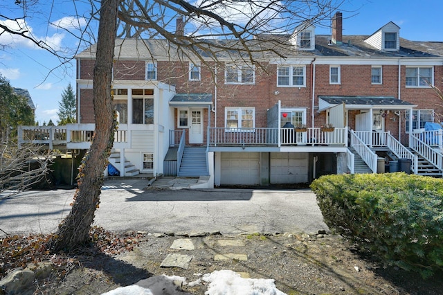 view of front of property with an attached garage, a chimney, and brick siding