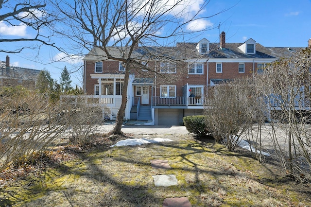 view of front of home with a garage, covered porch, brick siding, and a chimney