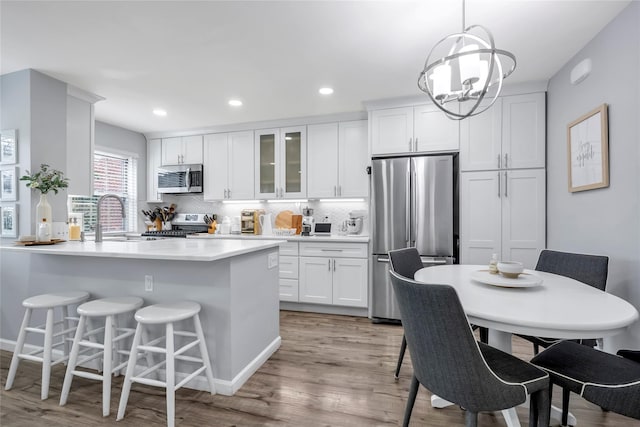 kitchen with white cabinets, a breakfast bar, stainless steel appliances, and a sink