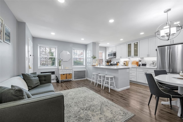 living area featuring dark wood-style floors, baseboards, a notable chandelier, and recessed lighting
