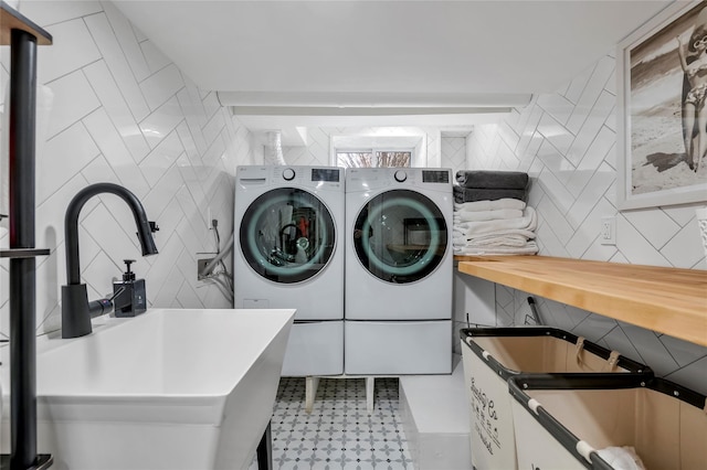 laundry room featuring laundry area, washer and clothes dryer, a sink, and tile walls