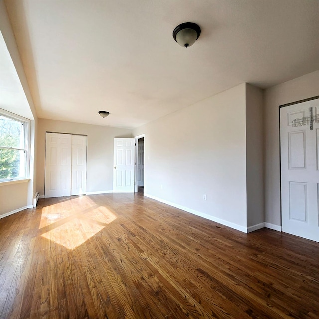 unfurnished bedroom featuring dark wood-style floors, a closet, and baseboards