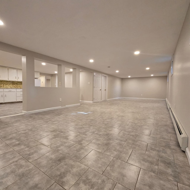 basement with recessed lighting, baseboards, baseboard heating, and refrigerator