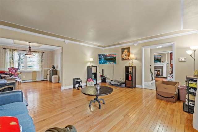 living room with baseboards, a lit fireplace, hardwood / wood-style flooring, and crown molding