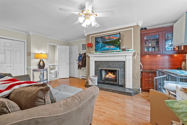 living area featuring crown molding, light wood finished floors, a baseboard radiator, a premium fireplace, and ceiling fan