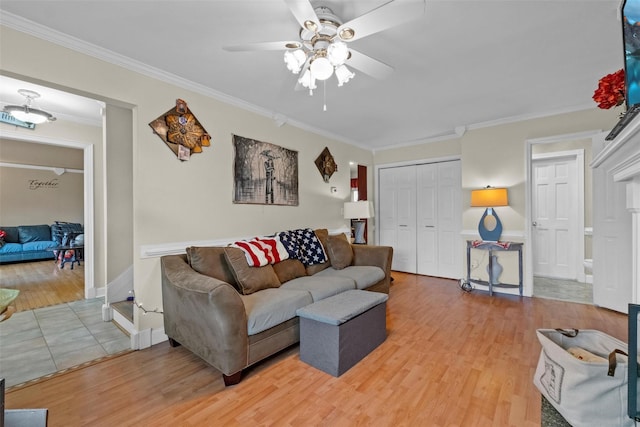 living area featuring ceiling fan, light wood finished floors, baseboards, and crown molding