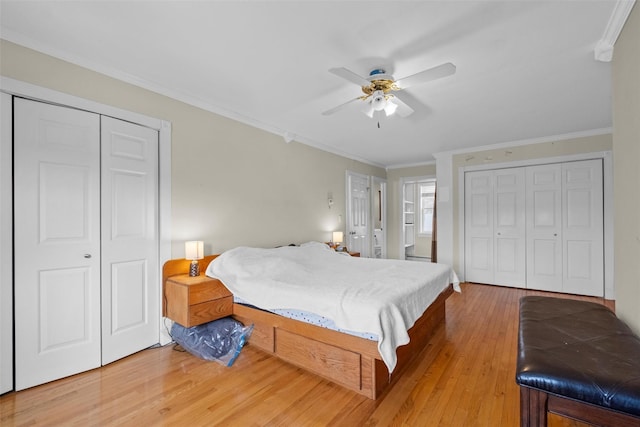 bedroom with ornamental molding, a ceiling fan, two closets, and wood finished floors