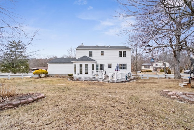 back of property featuring fence, a deck, and a yard