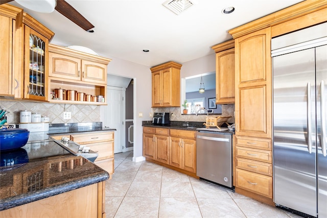 kitchen with visible vents, glass insert cabinets, appliances with stainless steel finishes, a sink, and light tile patterned flooring