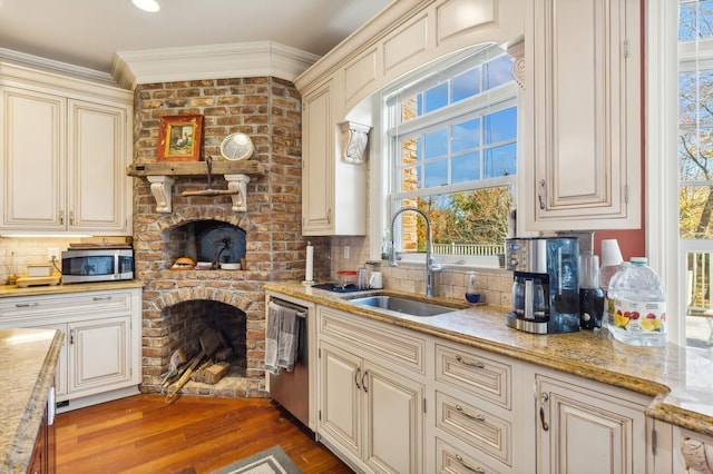 kitchen featuring stainless steel appliances, a sink, cream cabinetry, tasteful backsplash, and crown molding