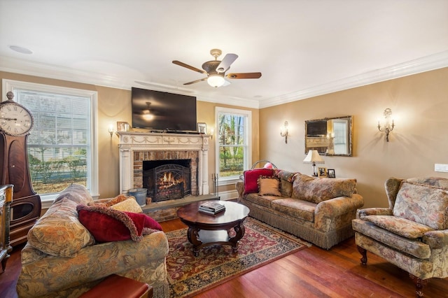 living area featuring ornamental molding, a ceiling fan, a brick fireplace, and wood finished floors