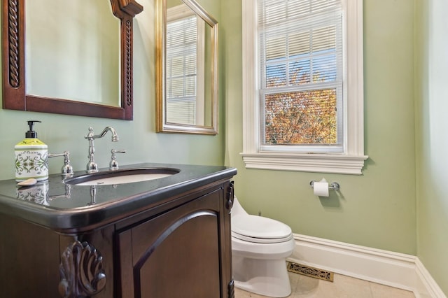 half bathroom with tile patterned flooring, toilet, vanity, visible vents, and baseboards