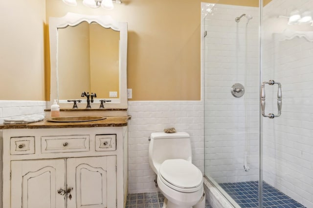 bathroom with tile walls, toilet, wainscoting, a shower stall, and vanity