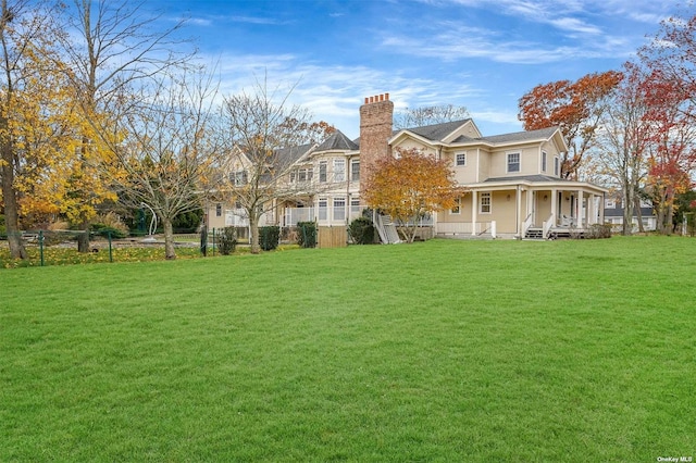 back of property with a chimney, fence, and a lawn