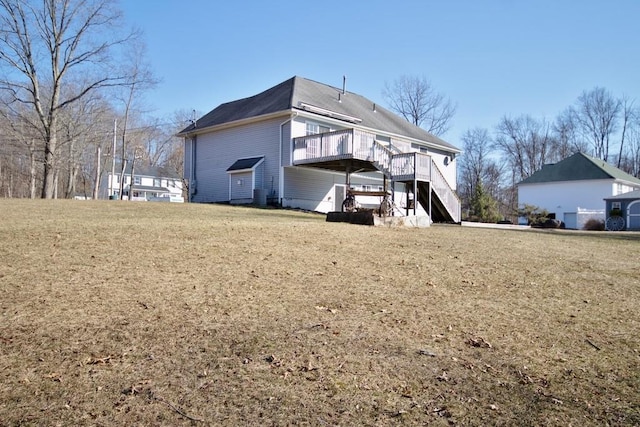 back of house featuring stairway, a lawn, and a deck