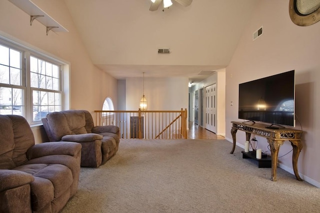 living area featuring baseboards, carpet, visible vents, and high vaulted ceiling