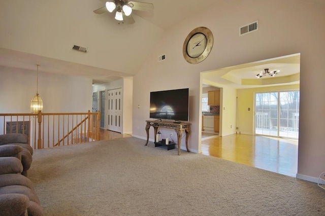 living room featuring visible vents, light carpet, high vaulted ceiling, and ceiling fan with notable chandelier