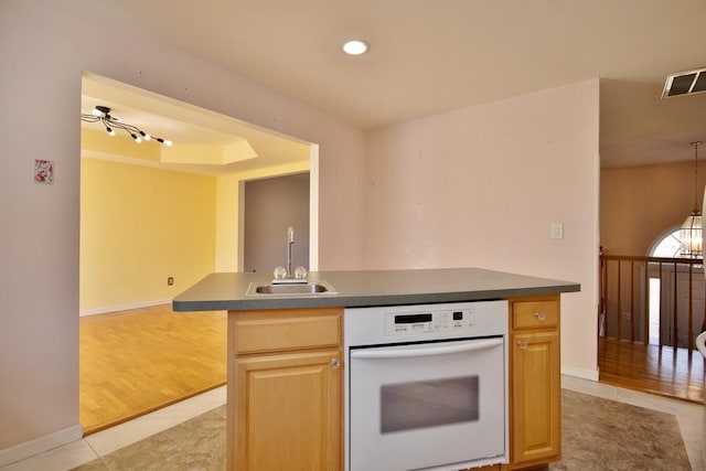 kitchen featuring visible vents, light brown cabinets, light tile patterned floors, white oven, and a sink