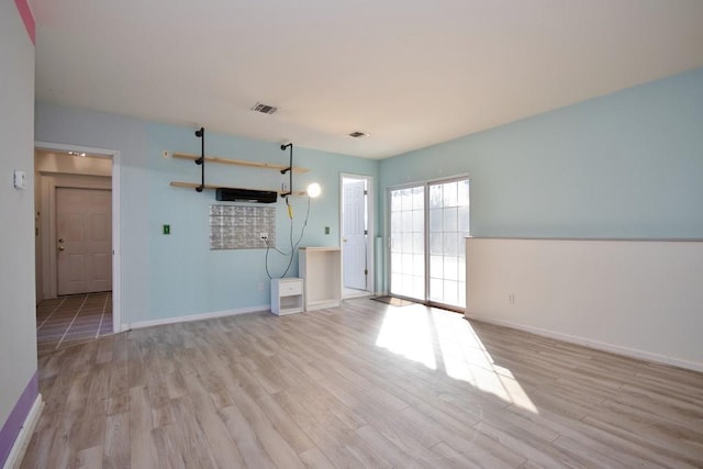 unfurnished living room featuring wood finished floors, visible vents, and baseboards