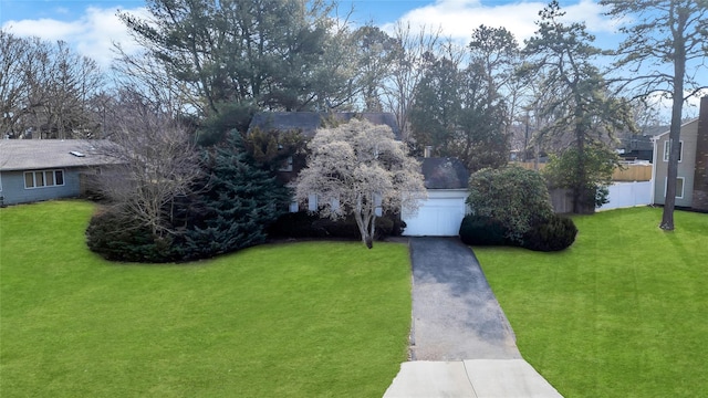 view of front of property featuring driveway, a front lawn, and fence