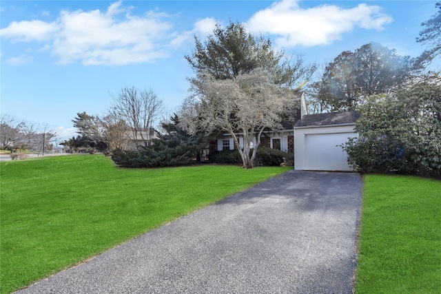 view of front of property with an attached garage, aphalt driveway, and a front yard