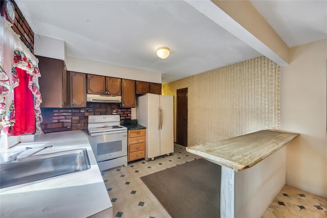 kitchen featuring under cabinet range hood, white appliances, a sink, light countertops, and light floors