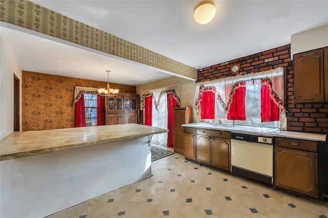 kitchen with white dishwasher, light countertops, light floors, an inviting chandelier, and pendant lighting