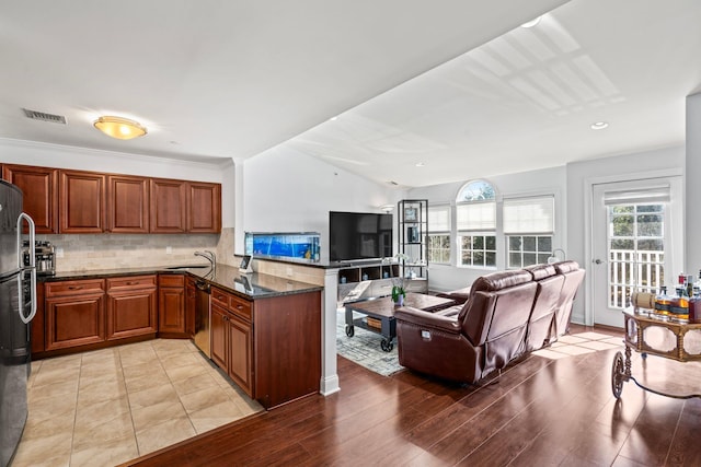 kitchen with a peninsula, stainless steel appliances, a sink, visible vents, and tasteful backsplash