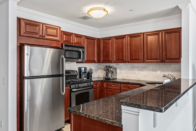 kitchen featuring visible vents, appliances with stainless steel finishes, a sink, dark stone countertops, and a peninsula