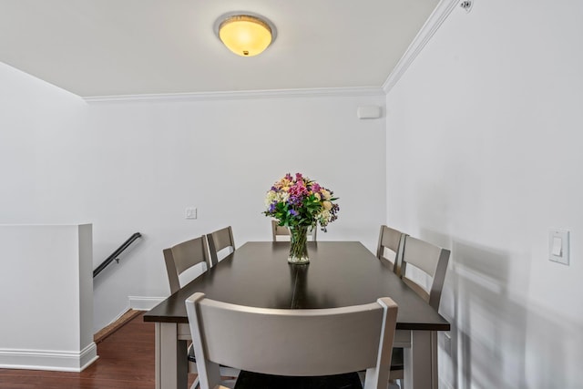 dining area with dark wood-type flooring, crown molding, and baseboards