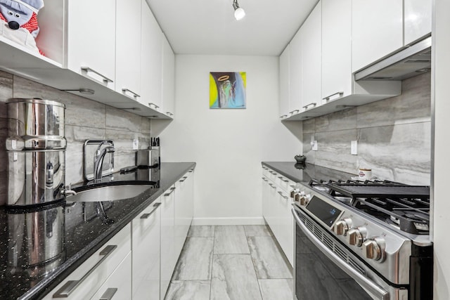 kitchen with a sink, white cabinetry, gas stove, decorative backsplash, and dark stone countertops