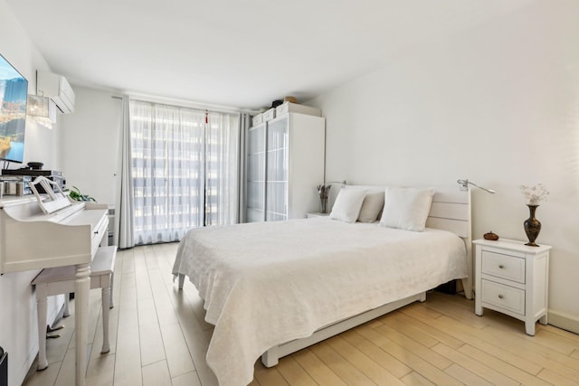 bedroom with a wall unit AC and light wood-style floors