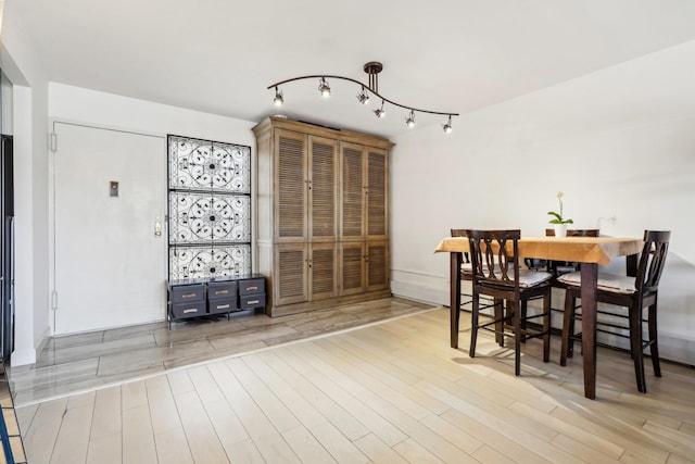 dining space featuring rail lighting and wood finished floors