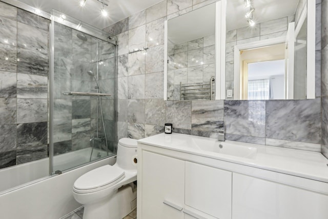 full bath featuring tile walls, toilet, shower / bath combination with glass door, vanity, and backsplash