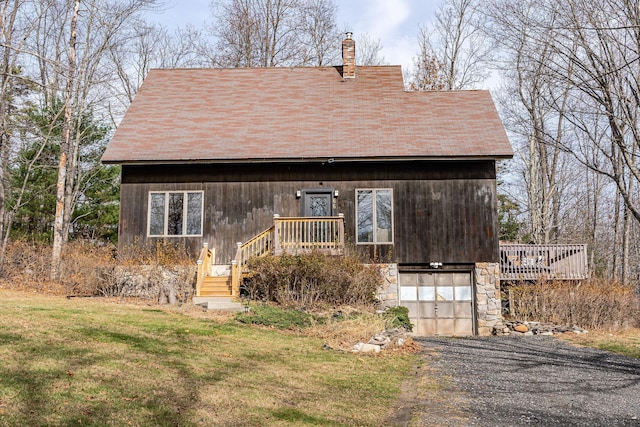 view of front facade with driveway, stone siding, a front yard, an attached garage, and a chimney