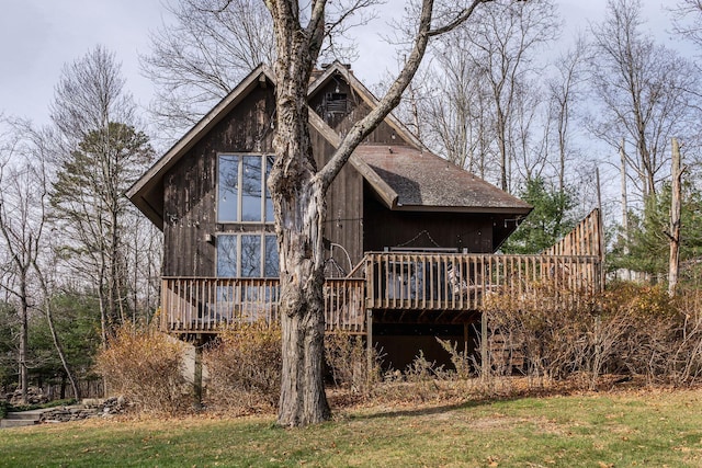 back of house with a deck, a lawn, and a shingled roof