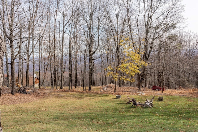 view of yard with a wooded view and a fire pit