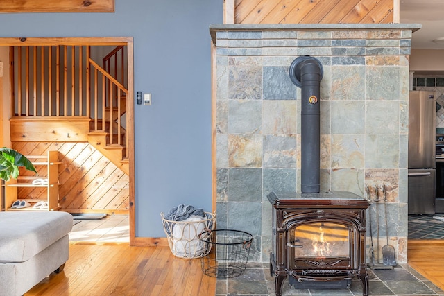 details with wood finished floors, a wood stove, and freestanding refrigerator