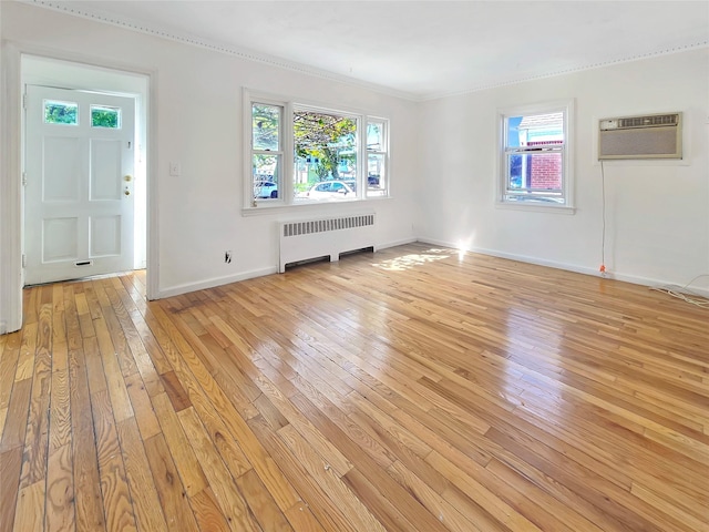 unfurnished living room with light wood finished floors, radiator heating unit, a wall mounted AC, and baseboards