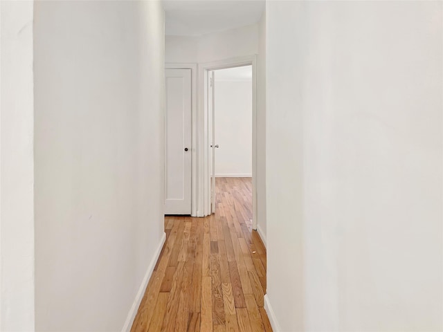 hallway with light wood-type flooring and baseboards