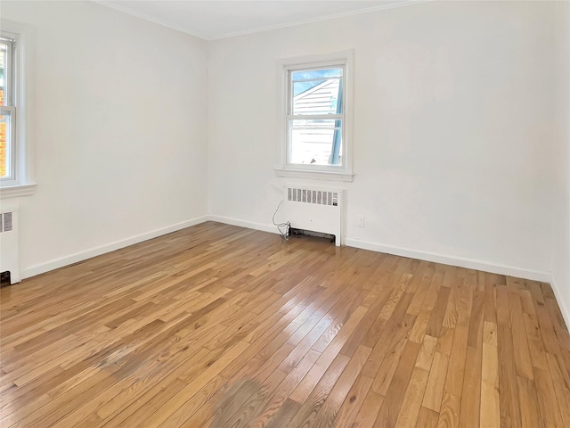 empty room featuring light wood-style floors, radiator, and baseboards