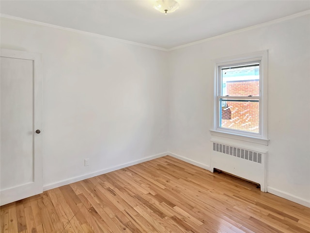 empty room featuring light wood-type flooring, radiator, crown molding, and baseboards