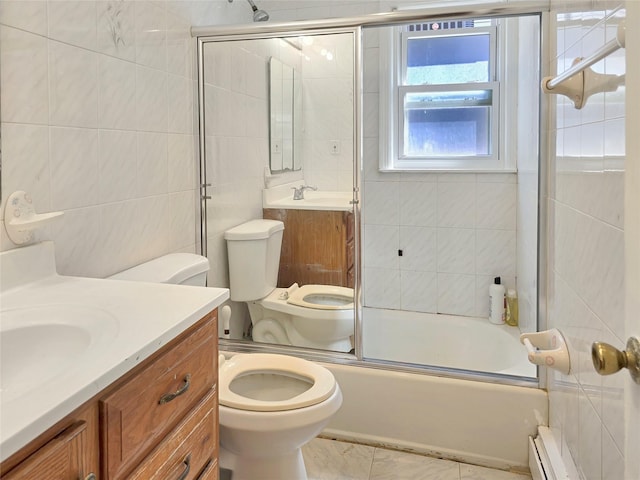 full bathroom featuring toilet, a baseboard heating unit, vanity, tile walls, and combined bath / shower with glass door