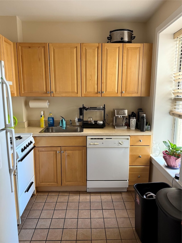 kitchen with light tile patterned floors, light brown cabinets, white appliances, a sink, and light countertops