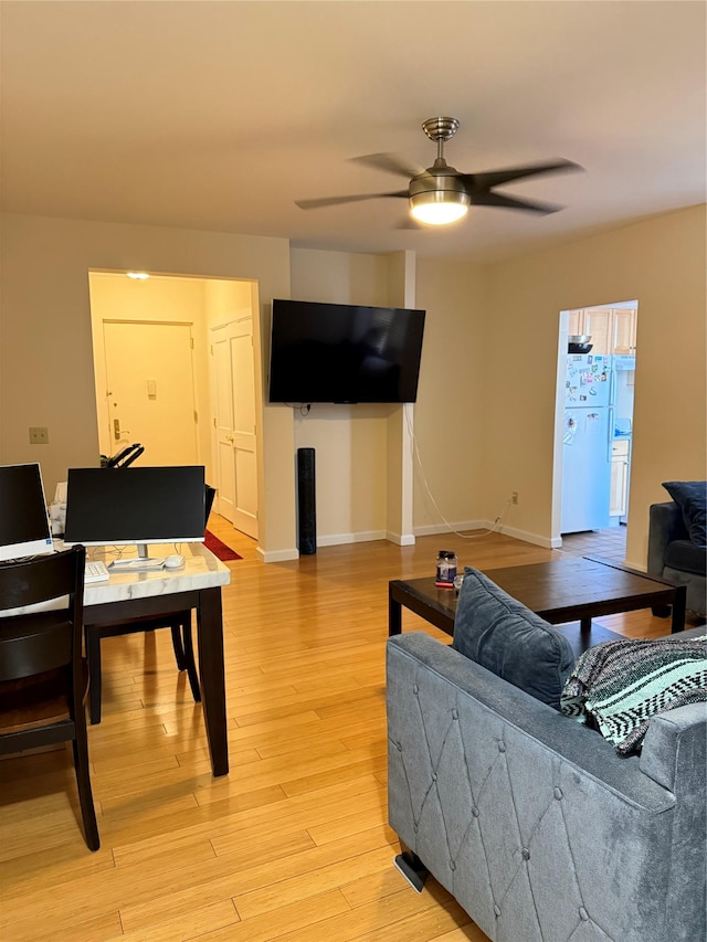 living room featuring light wood-style floors, baseboards, and a ceiling fan